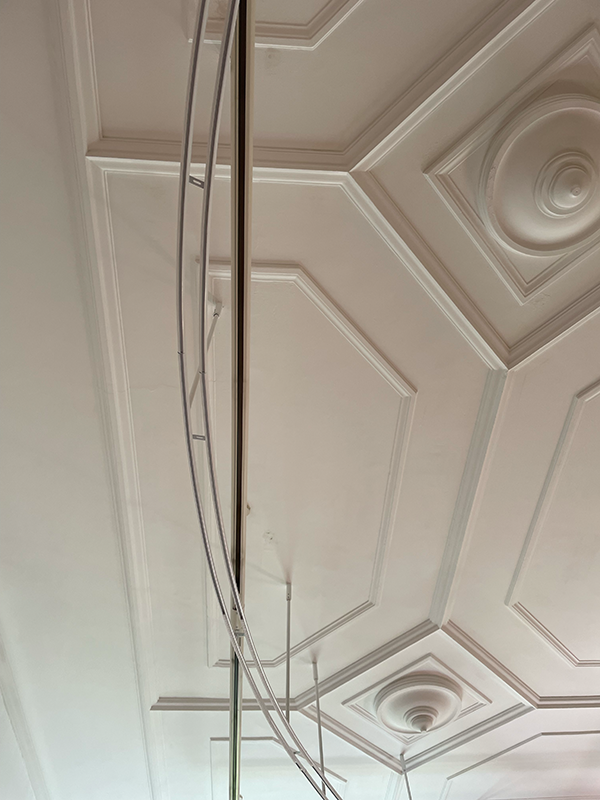 Ceiling with decorative molding and a large circular mirror reflecting the patterns.