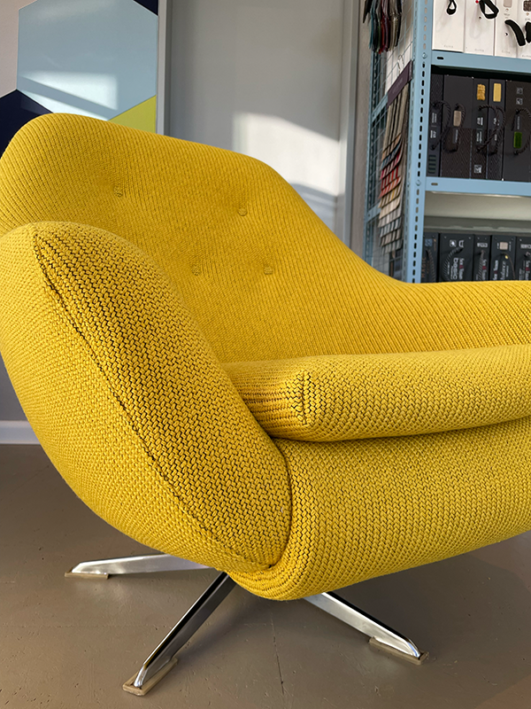 Modern yellow upholstered swivel chair with metal legs in an indoor setting.